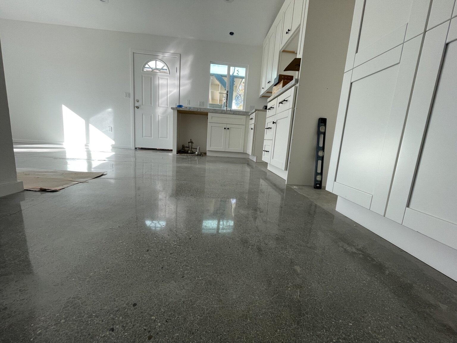 Completed garage conversion ADU with white kitchen and polished concrete floor