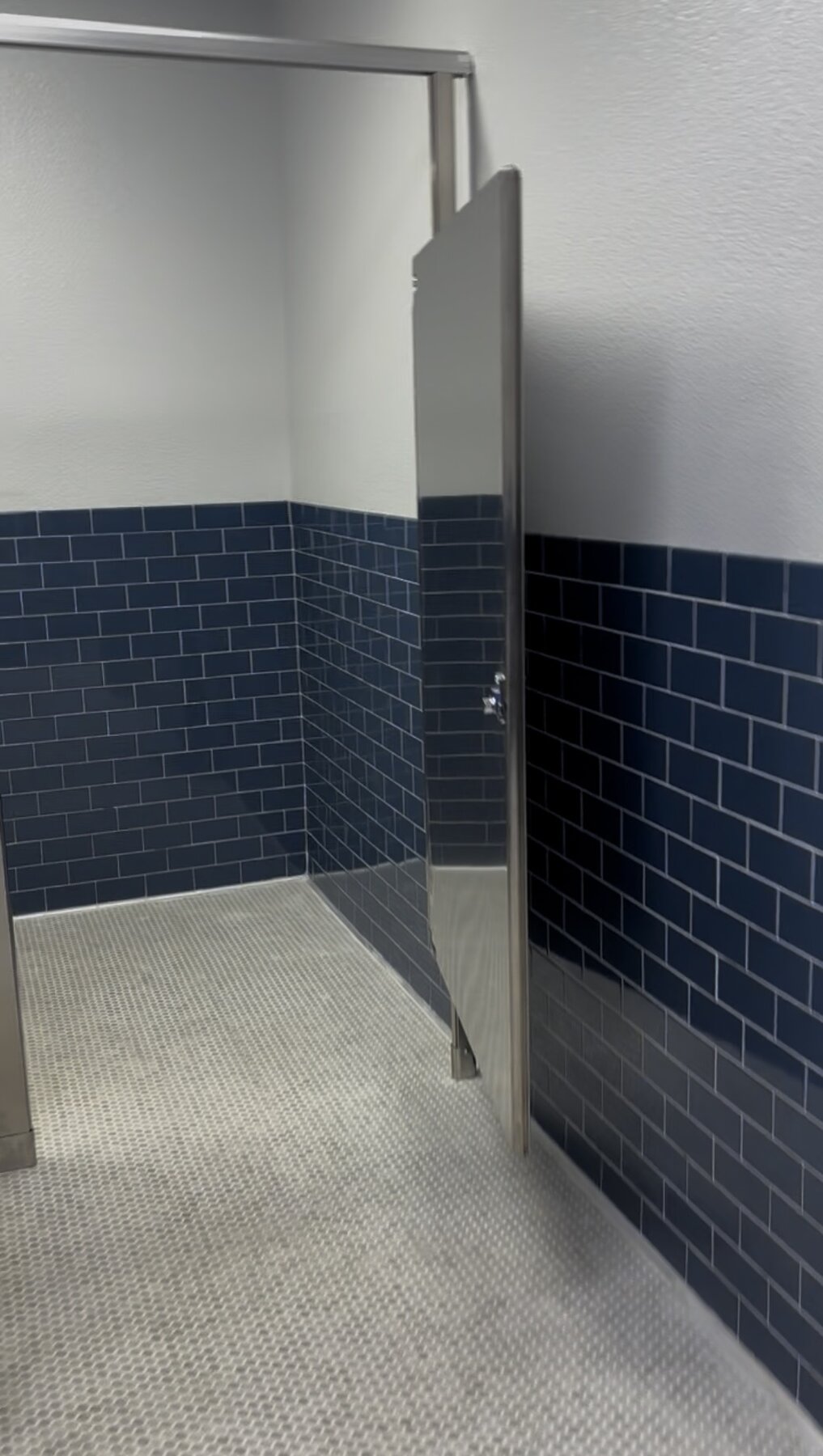 Completed commercial restroom with blue tile and stainless steel partition