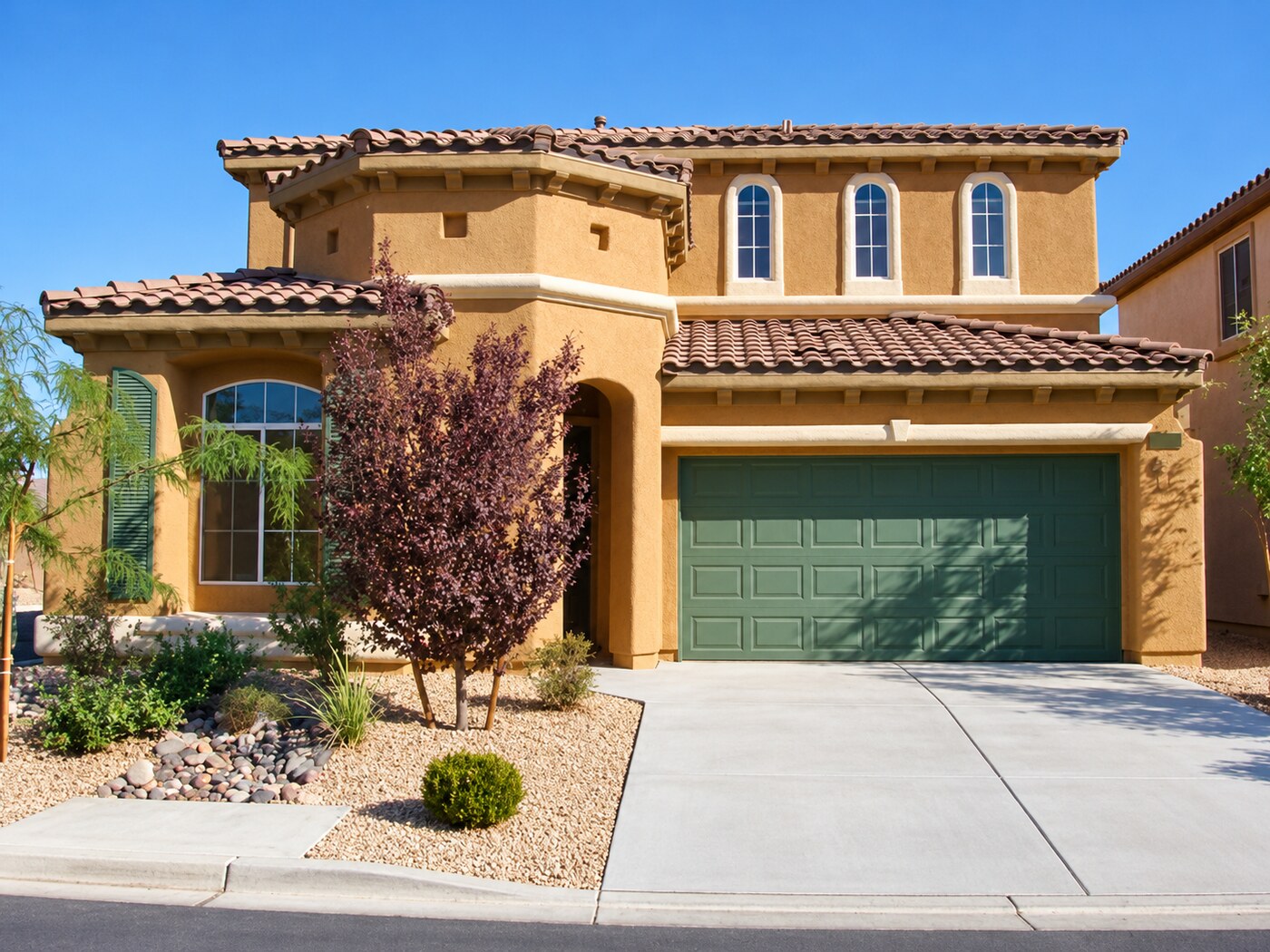 Two-story Mediterranean-style residence with green garage door
